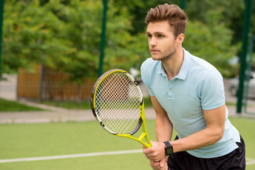 Handsome young sportsman playing tennis