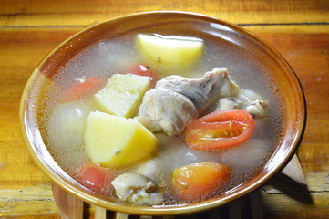boiled chicken leg with potato and tomato soup on bowl
