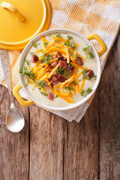 Potato puree soup with bacon and cheddar close-up in a pan. Vertical top view
