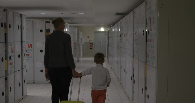 Mother and son coming to baggage room and leaving travel bag in the locker