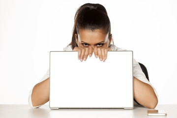 young happy and shy woman hiding behind a laptop