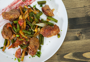 chicken liver with bacon, mushrooms and green beans on wooden table