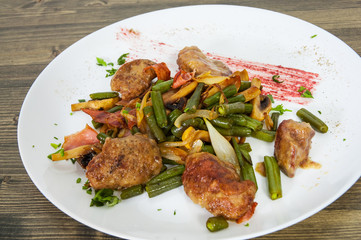 chicken liver with bacon, mushrooms and green beans on wooden table
