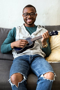 Handsome young black man playing the guitar at home.