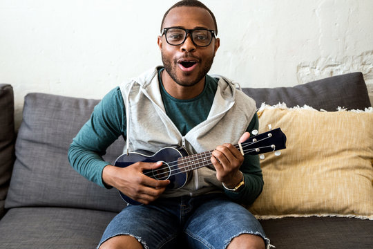 Handsome young black man playing the guitar at home.