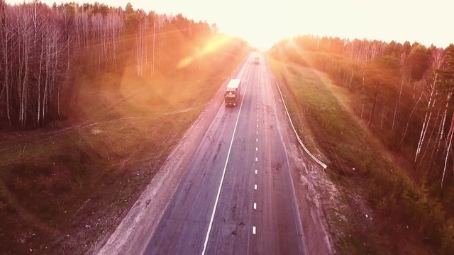 Flights above highway road at the sunset. Aerial view of trucks on the road.