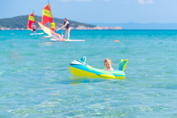 Beautiful baby girl playing in a inflatable boat at the beach