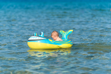 Beautiful baby girl playing in a inflatable boat at the beach