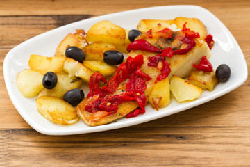 codfish with red pepper and fried potato on white dish
