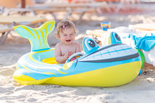 Beautiful baby girl playing in a inflatable boat at the beach