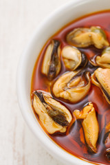 mussels with sauce in white dish on white wooden background