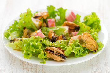 salad with mussels on white dish on white wooden background