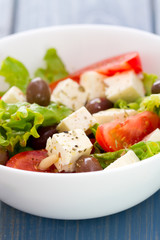 salad cheese with vegetables in white bowl on blue background