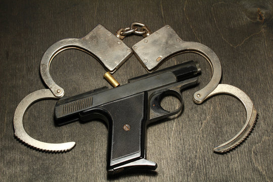 gun and handcuffs on black wooden background
