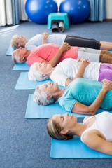 Naklejka premium Instructor performing yoga with seniors
