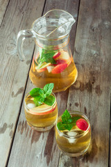 Two glass and carafe of green tea with mint and apples