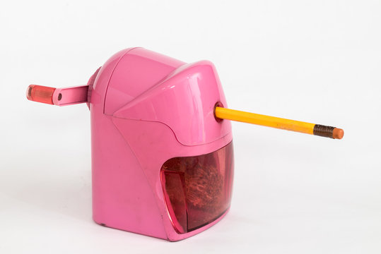 pink rotary pencil sharpener with yellow pencil isolated on whit