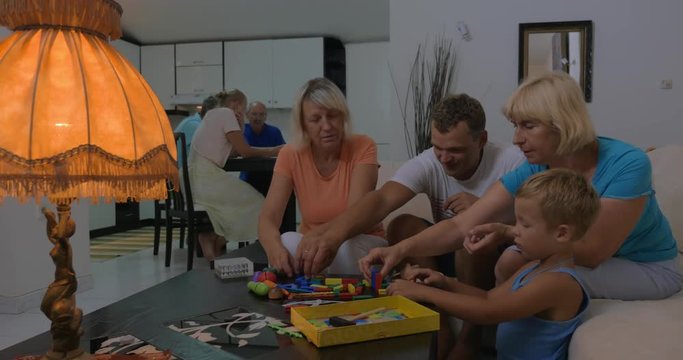 Father and two grandmothers spending time with a child. They playing with construction kits together