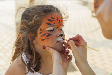 Girl getting her face painted by painting artist.