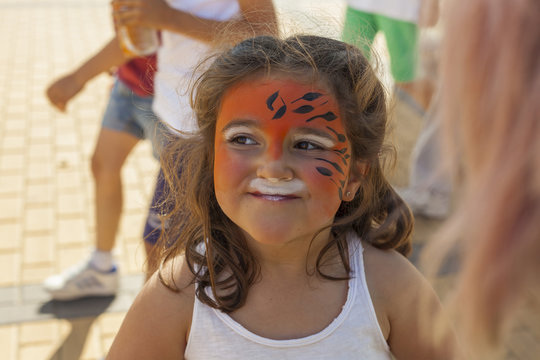 Girl getting her face painted by painting artist.