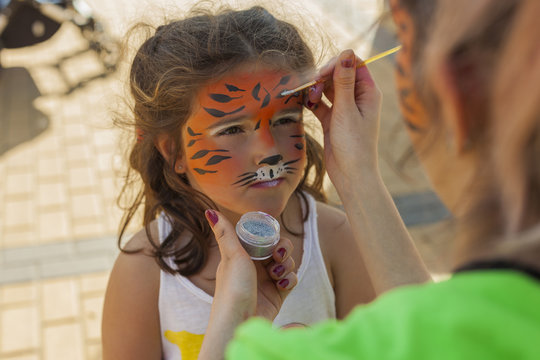 Girl getting her face painted by painting artist.