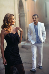 Man in white suit walks to a stunning woman in black dress