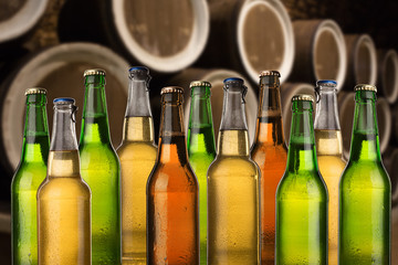 Group of cold wet beer bottles in the cellar with vintage kegs
