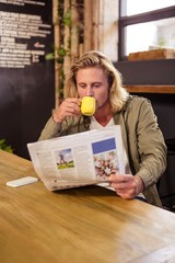 Man drinking a coffee while is reading a newspaper
