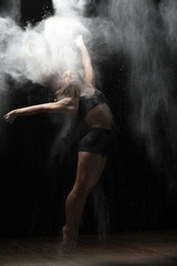 Obraz na płótnie Canvas Ballerina dancing with flour on black background