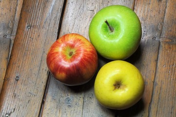 Three apples on wooden background
