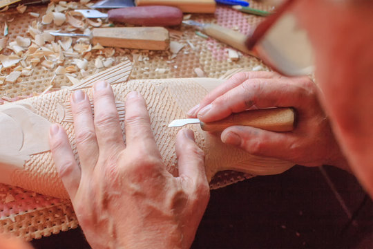 master carves wooden fish. woodcarving closeup 