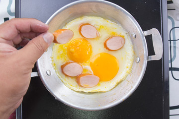 Chef putting slice of sausage to the pan