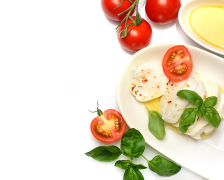 Delicious cheese mozzarella, tomato and basil leaves in white plate over white background