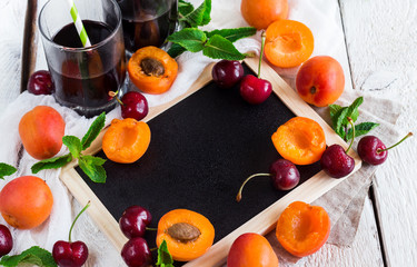 Black board with organic ripe apricots and cherries