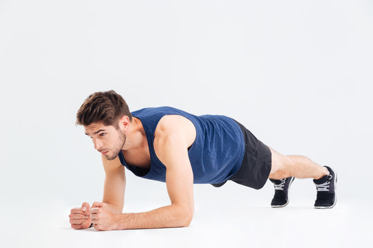 Focused handsome young sportsman doing plank core exercise