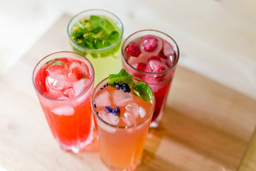 Four homemade refreshing summer cocktails and drinks with ice fresh berries, strawberry, raspberry and grapefruit on wooden cutting Board top view