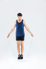 Full length portrait of a man jumping with skipping rope