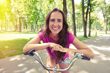 Fototapeta na wymiar Close-up of smiling lady posing with hands resting on handlebar