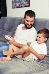 Dad and son are having fun playing videogame using joysticks