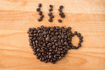 coffee beans in cup shape and smoke on wooden background