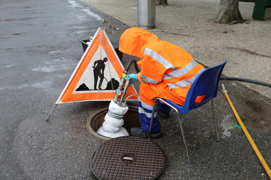 Worker At The Draining Manhole In Orange Special Clothing