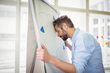 Fototapeta premium Tired businessman holding whiteboard in office