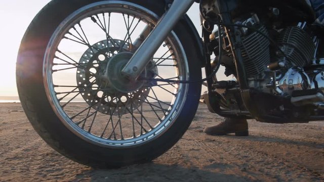 Close up dolly shot of motorcyclist and his motorbike on the road during sunset