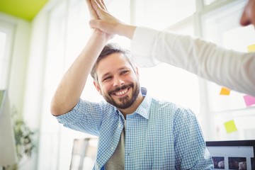 Smiling coworkers giving high-five in creative office
