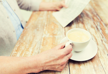 senior woman with coffee reading newspaper at home