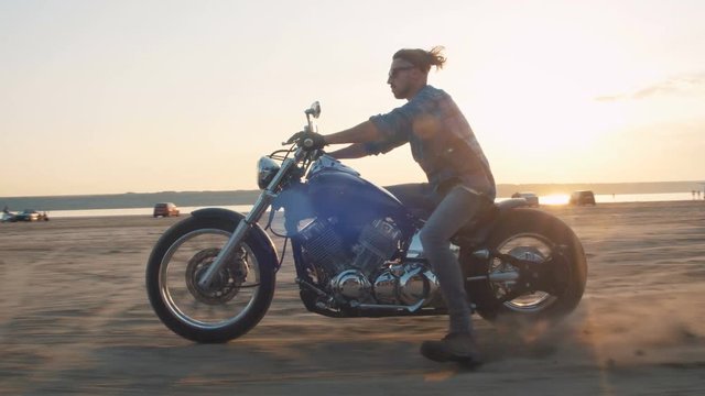 Motorcyclist driving his motorbike on the road during sunset near the water
