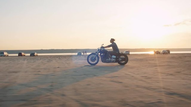 Motorcyclist driving his motorbike on the road during sunset near the water
