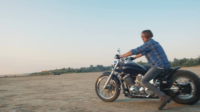Motorcyclist driving his motorbike on the road during sunset near the water