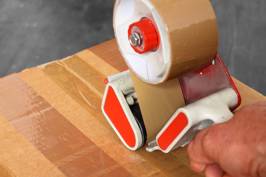 Taping box tape dispenser / Man taping a cardboard box with a tape dispenser