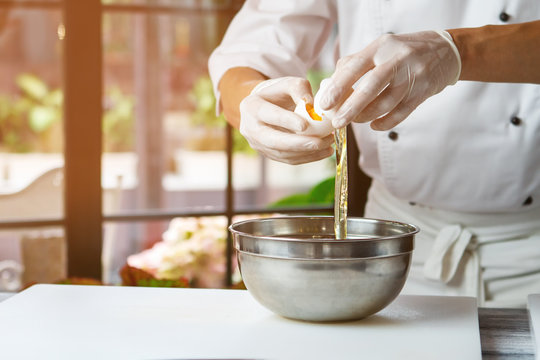Hands break an egg. Raw egg pouring into bowl. Chef separates white from yolk. Ingredient for high-protein dish.